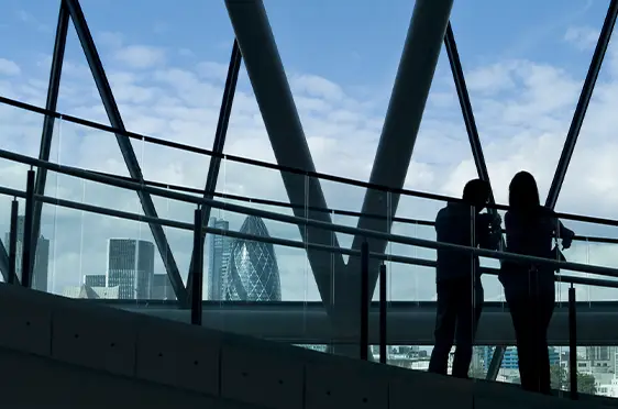 Photo of sillhouetted people loking out from skyscraper
